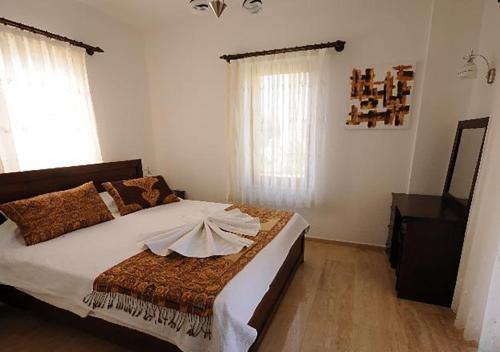 a bedroom with a large bed with white walls and windows at RUMUZLUKONUT in Bodrum City