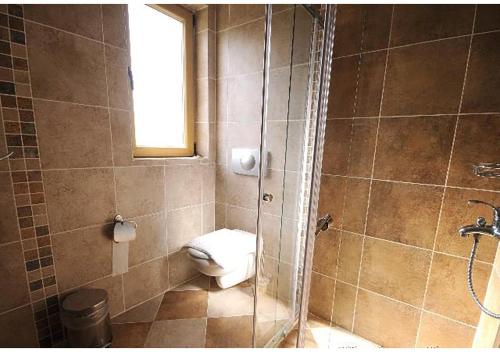 a bathroom with a toilet and a shower with a window at RUMUZLUKONUT in Bodrum City