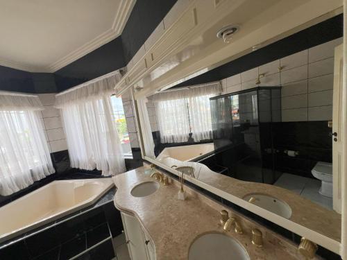 uma casa de banho com 2 lavatórios e uma banheira e um tubermott em Suíte de Luxo no centro, com hidromassagem e closet em Sinop