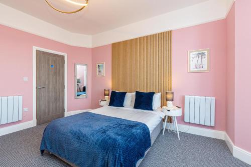 een slaapkamer met een groot bed met roze muren bij Beachfront Apartment 3 Bedrooms Sleeps 7 - Newly Refurbished in Morecambe