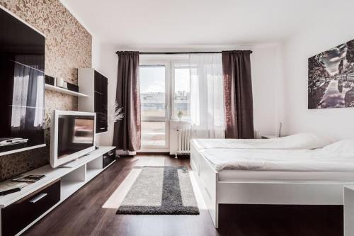 ein weißes Schlafzimmer mit einem großen Bett und einem TV in der Unterkunft Top floor sunny studio with terrace in Prag