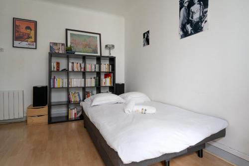 - une chambre avec un lit et une étagère avec des livres dans l'établissement Appartement Bolivar - Welkeys, à Paris