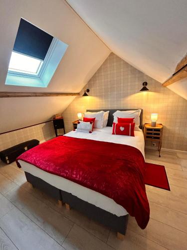 une chambre avec un grand lit avec des oreillers rouges dans l'établissement La Grange Aux Hirondelles - Chambre Ch'ti, à Woignarue