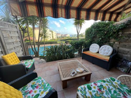 a patio with two couches and a table and a view at T2 rez de jardin plage piscines vue mer parking terrasse commerces in Six-Fours-les-Plages