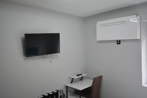 a room with a chair and a tv on a wall at Stadthotel Das Villach in Villach