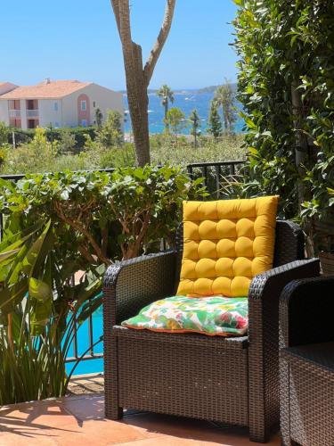 - une chaise en osier avec un oreiller jaune sur la terrasse dans l'établissement T2 rez de jardin plage piscines vue mer parking terrasse commerces, à Six-Fours-les-Plages