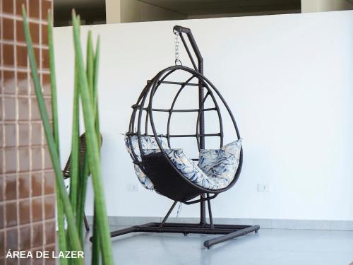 a swing chair on a stand next to a plant at ApartDamani - Aptos por Temporada no centro in Foz do Iguaçu