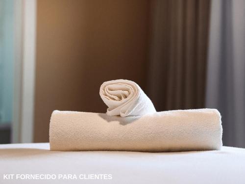 a towel with a rose on top of a bed at ApartDamani in Foz do Iguaçu