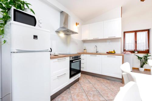 a kitchen with white cabinets and a refrigerator at Charming House Nino with a fenced yard in Krmed