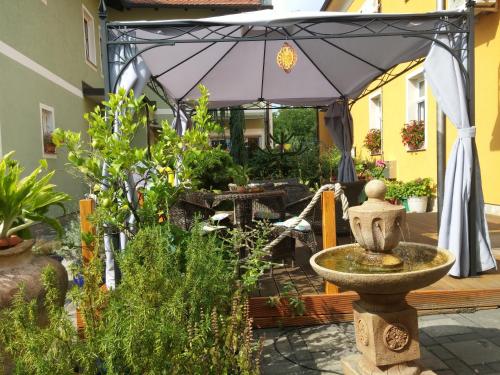 a garden with a fountain and an umbrella at Hostel Sonce in Ptuj