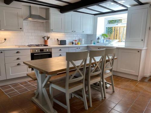 a kitchen with white cabinets and a wooden table and chairs at Holmfirth Hideout in Holmfirth