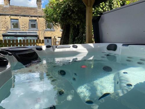 a hot tub with water in front of a house at Holmfirth Hideout in Holmfirth