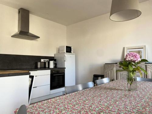 une cuisine avec une table avec un vase de fleurs dessus dans l'établissement Résidence 224-pleneuf Val Andre - Maisons & Villas pour 6 Personnes 704, à Pléneuf-Val-André