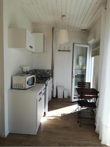 - une cuisine blanche avec un four micro-ondes et une table dans l'établissement Résidence 226-pleneuf Val Andre - Charmant studio de 20m², avec jardin privé. MAE-6764, à Pléneuf-Val-André