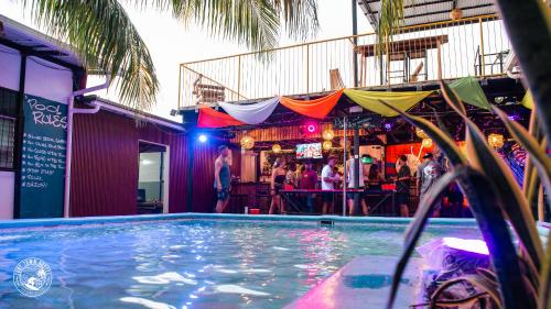 a swimming pool in front of a bar with people drinking at Surf Town Hostel in San Juan del Sur