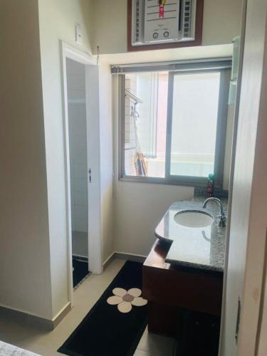 ein Bad mit einem Waschbecken und einem Fenster in der Unterkunft Flat na praia in Vila Velha