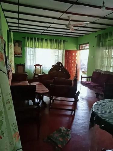 ein Wohnzimmer mit grünen Wänden sowie einem Tisch und Stühlen in der Unterkunft Dimuthu's house in Dikwella