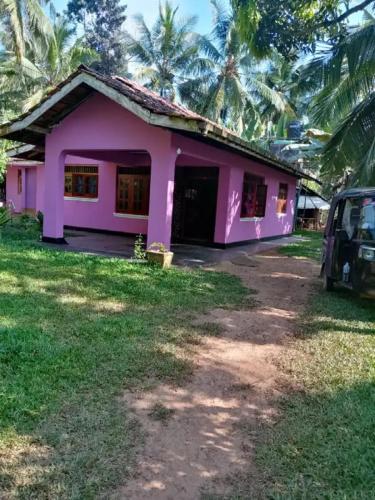 ein rosafarbenes Haus mit einem davor geparkt in der Unterkunft Dimuthu's house in Dikwella