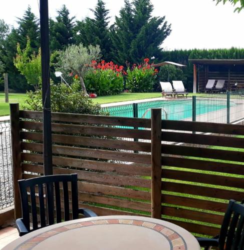 a table and chairs in front of a fence with a pool at CAN PLANAS , Estudio Familiar in Fonolleras