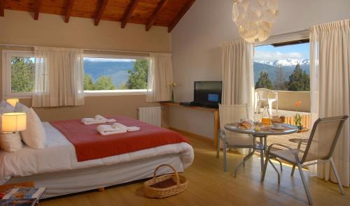 a bedroom with a bed and a table with a dining room at Las Nalcas Boutique Hotel & Mountain Spa in El Bolsón