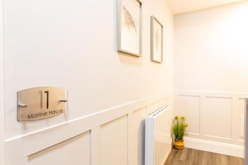 a kitchen with white cabinets and a shelf with a sign on the wall at Modern Seafront 2 Bedroom Apartment - Brand New in Morecambe
