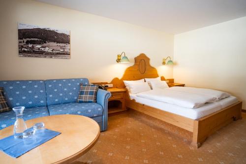 a room with a bed and a couch and a table at Hotel Alpengasthof Löwen in Bad Hindelang