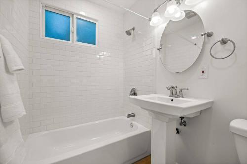 a white bathroom with a sink and a tub and a mirror at American Riviera Oasis Close to Beach and Downtown in Santa Barbara