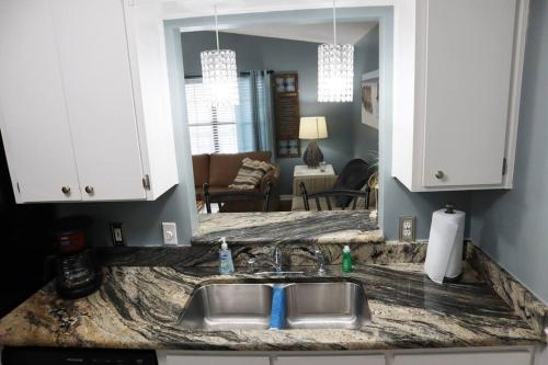 a kitchen counter with a sink and a living room at Lazy Palm Panama City Beach Free New 2023 Golf Cart! Across street From Beach! in Panama City Beach
