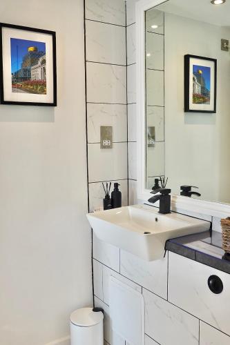 a white bathroom with a sink and a mirror at Modern Luxurious Apartment in Birmingham