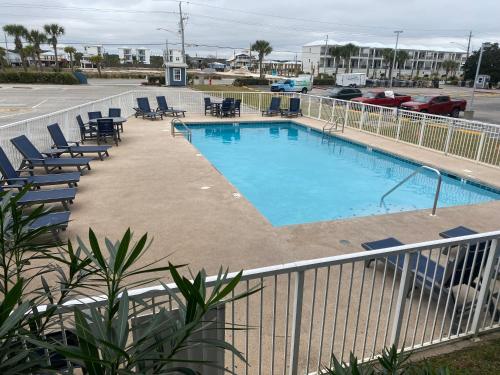 a swimming pool with lounge chairs next to a parking lot at Little Miss Magic in Gulf Shores