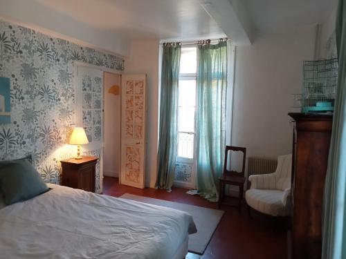 a bedroom with a bed and a window and a chair at Le Mas Palegry Chambres d'hôtes Perpignan in Perpignan