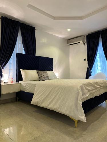 - une chambre avec un grand lit et 2 fenêtres dans l'établissement 7th Heaven Homes, à Ibadan