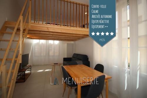 a dining room with a wooden table and a staircase at La Menuiserie in Gap