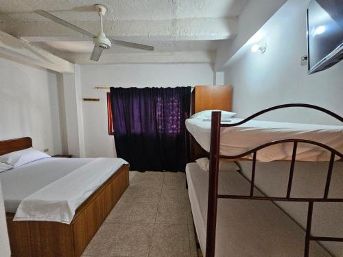 a bedroom with a bed and a window with a fan at Hotel El Imperio in Santa Marta
