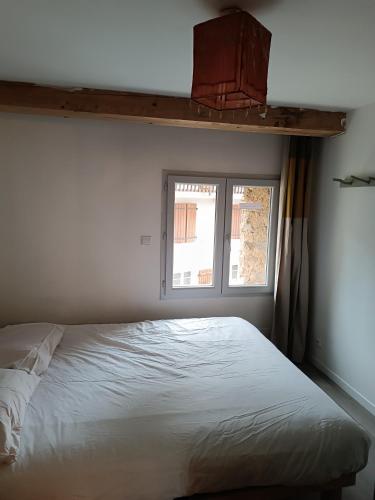 - un lit blanc dans une chambre avec fenêtre dans l'établissement Charmante maison village QUERIGUT, à Quérigut