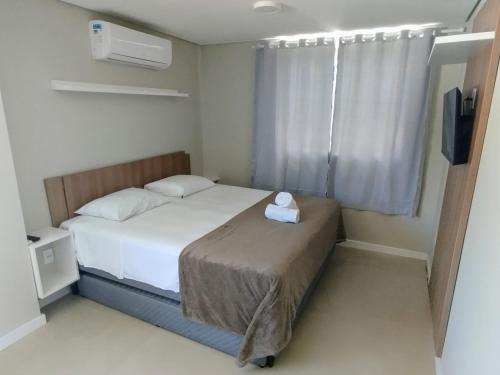 um pequeno quarto com uma cama e uma televisão em Pousada Bombinhas House em Bombinhas