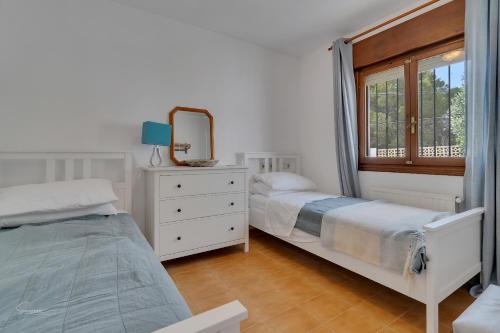 2 letti in una camera da letto con specchio e cassettiera di Casa Nico- by Aldertons a Teulada