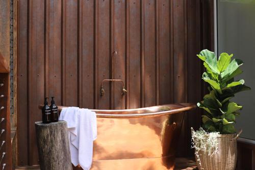 a bathroom with a copper tub next to a wooden wall at Rainforest Gardens - Luxury Hillside Accomodation with Views to Bay & Islands in Mount Cotton