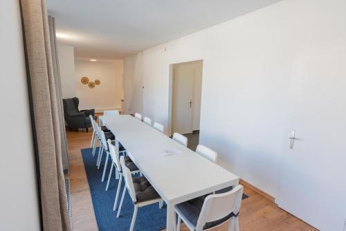 Habitación larga con mesas blancas y sillas blancas. en Luxury Penthouse - Augarten, en Viena