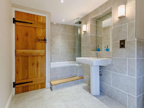 La salle de bains est pourvue d'un lavabo, d'une baignoire et d'une porte. dans l'établissement 1 Bed in Marlborough 65123, à Fyfield
