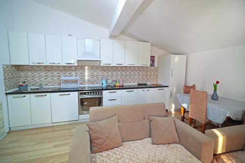 una cucina con armadi bianchi e un soggiorno con divano. di Prizren Apartment's a Prizren