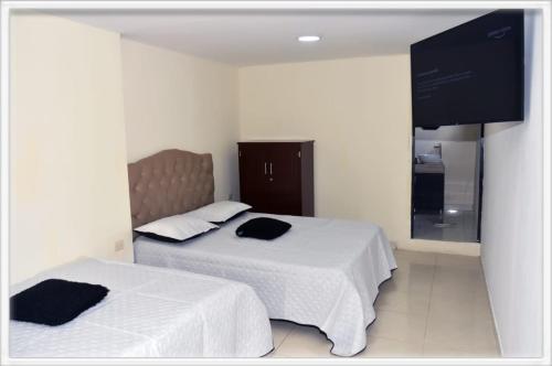 a bedroom with two beds and a flat screen tv at Familia angel in Dosquebradas