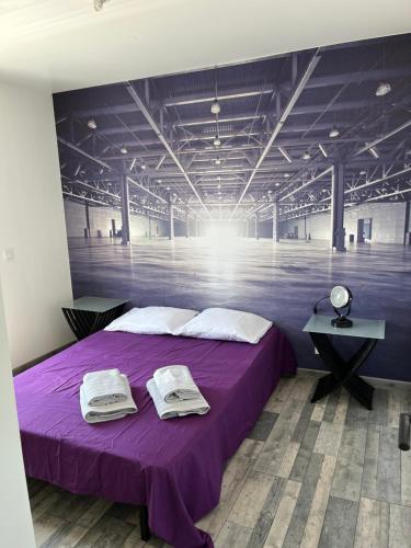 um quarto com uma cama roxa com toalhas em Complexe 10 personnes piscine chauffée privée et jacuzzi em Coudot