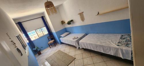 um quarto azul e branco com uma cama e uma janela em Afrolar - Vizinhas de Iemanjá em Salvador
