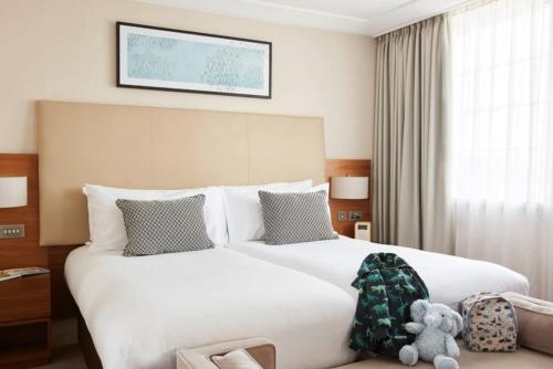 Un dormitorio con una gran cama blanca con un osito de peluche. en Lonsdale House Luxury Apartments en Ulverston