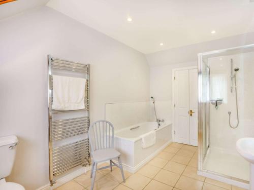 a bathroom with a tub and a toilet and a chair at 4 bed in Bowcombe IC017 in Bowcombe