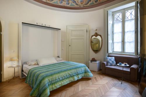 um quarto com uma cama, uma cadeira e uma janela em Il cielo in una stanza em Bérgamo