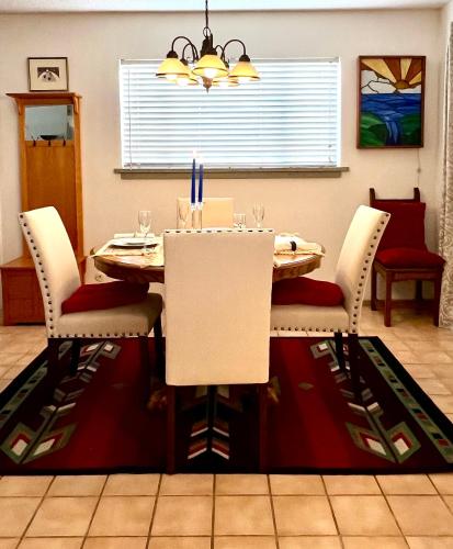 a dining room table with white chairs and a red rug at Downtown Historic East-Side Coyote House 2B 2BA in Santa Fe