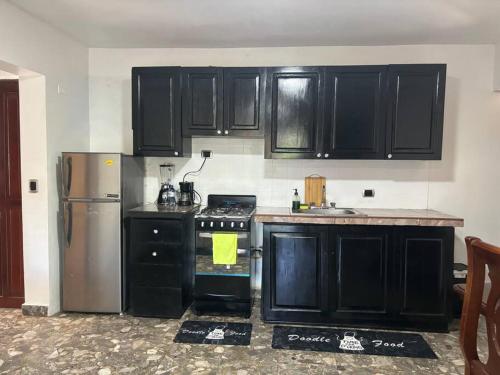 a kitchen with black cabinets and a stove and a refrigerator at Brisas del Mar 3 in San Felipe de Puerto Plata