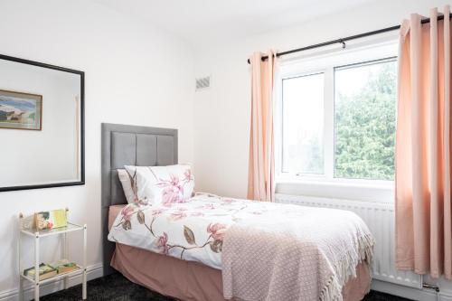 Entire 3 bedrooms home away from Home in Salford في مانشستر: غرفة نوم بسرير ونافذة